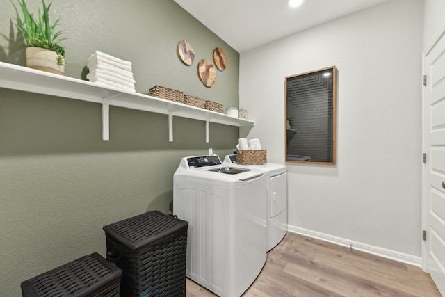 laundry room with washer and clothes dryer and light hardwood / wood-style floors