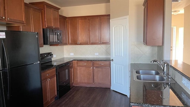 kitchen featuring dark wood-type flooring, sink, black appliances, dark stone countertops, and backsplash