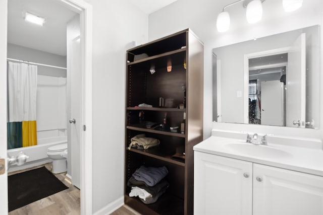 full bathroom featuring wood-type flooring, toilet, shower / bath combo with shower curtain, and vanity