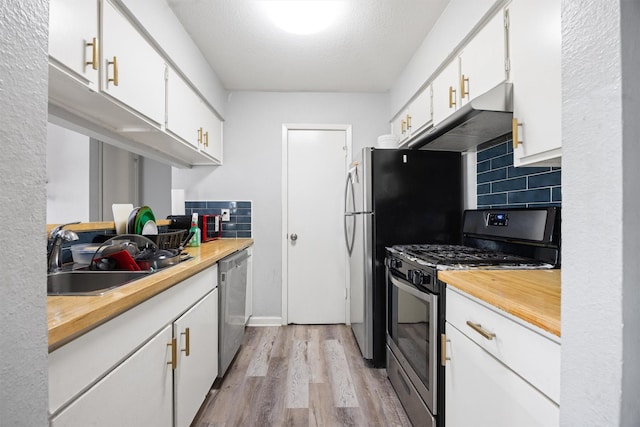 kitchen featuring sink, white cabinetry, stainless steel appliances, light hardwood / wood-style floors, and decorative backsplash