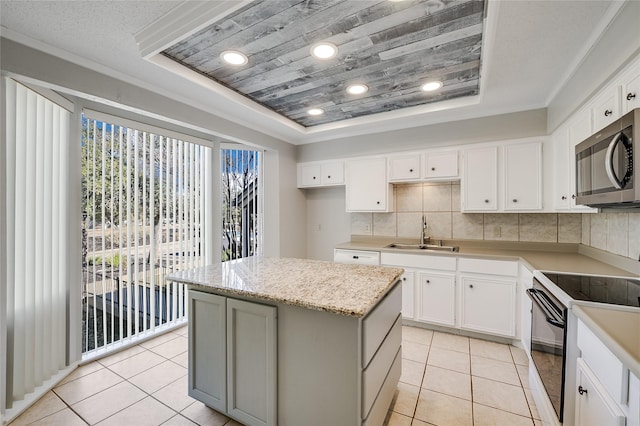 kitchen featuring a kitchen island, sink, white cabinets, a tray ceiling, and electric stove