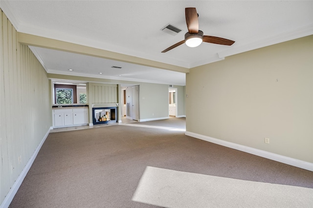 unfurnished living room with a multi sided fireplace, ornamental molding, light carpet, and ceiling fan