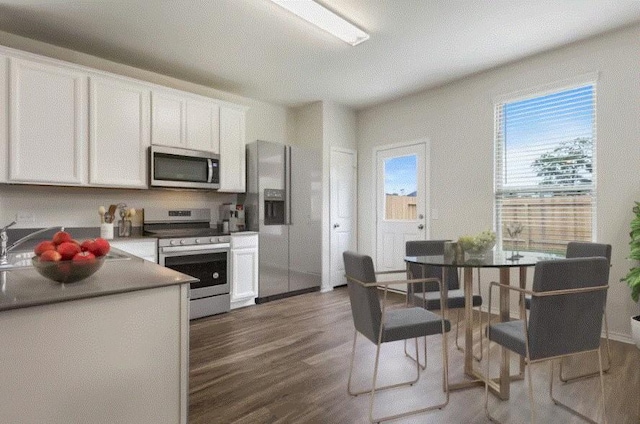 kitchen with appliances with stainless steel finishes, dark hardwood / wood-style flooring, and white cabinets