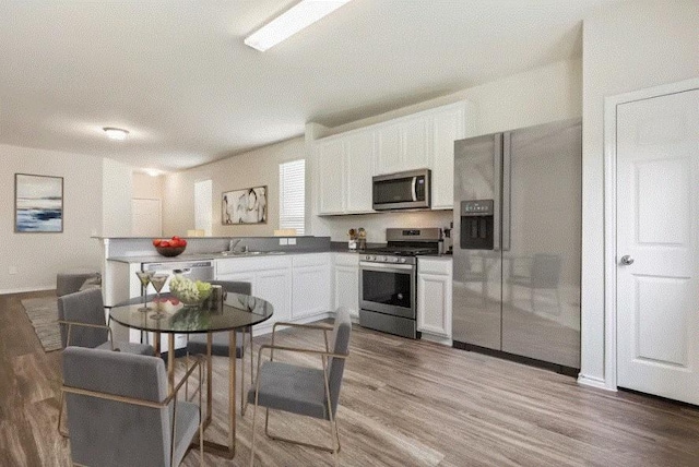 kitchen featuring appliances with stainless steel finishes, sink, hardwood / wood-style floors, and white cabinets