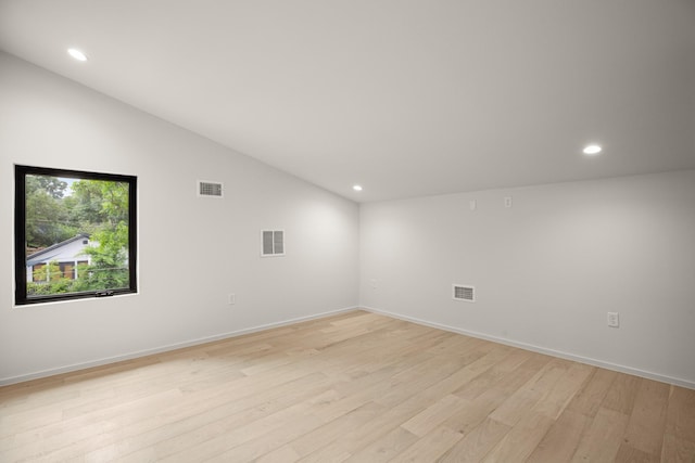 unfurnished room featuring lofted ceiling and light hardwood / wood-style flooring