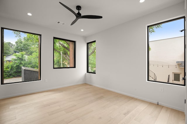 unfurnished room with a wealth of natural light, light hardwood / wood-style floors, and ceiling fan