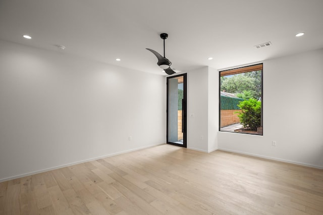 empty room featuring expansive windows and light hardwood / wood-style floors