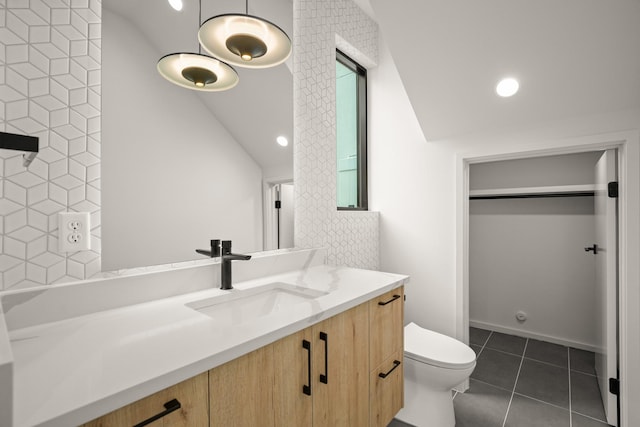 bathroom featuring tile patterned flooring, vanity, vaulted ceiling, and toilet