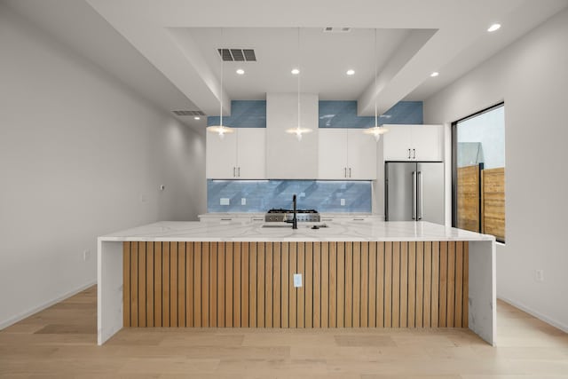 kitchen with white cabinetry, high quality fridge, and a large island