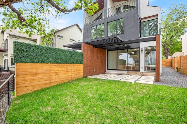 rear view of property featuring a patio area and a lawn