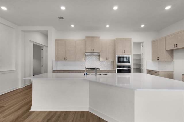 kitchen featuring light countertops, a large island with sink, visible vents, and appliances with stainless steel finishes