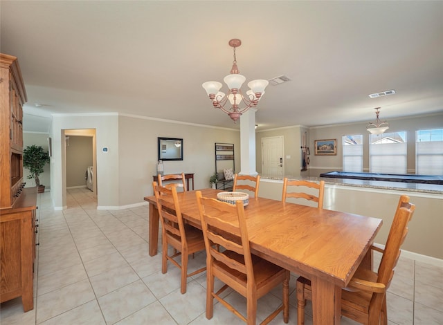 tiled dining area with ornamental molding, washer / clothes dryer, and a notable chandelier