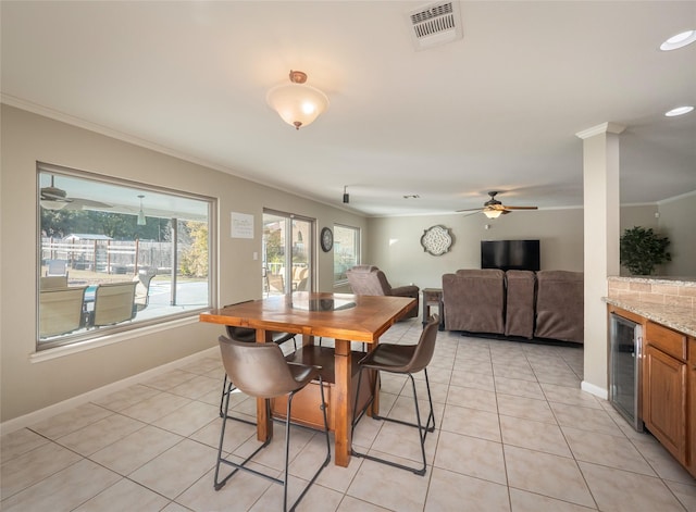 dining space with light tile patterned flooring, ornamental molding, and beverage cooler