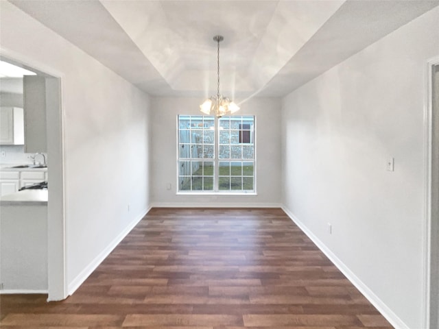 unfurnished dining area featuring a raised ceiling, sink, a chandelier, and dark hardwood / wood-style flooring