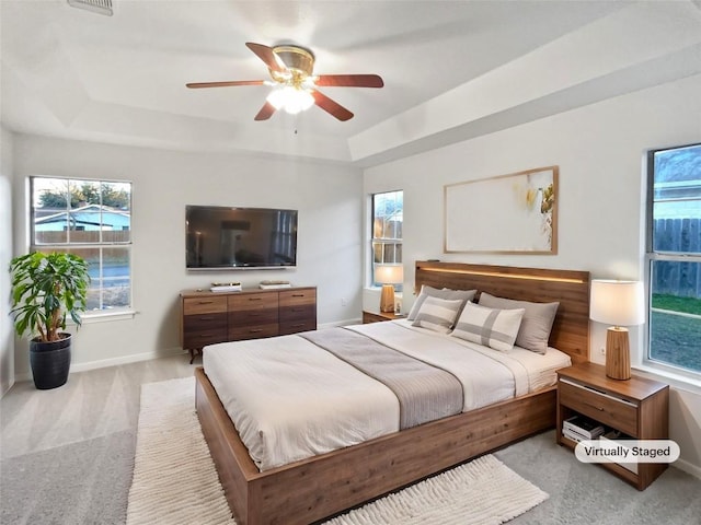 bedroom featuring light carpet, ceiling fan, and a tray ceiling