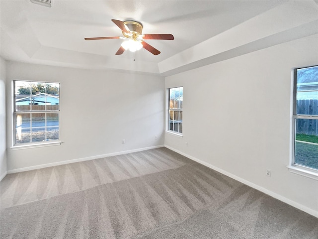 carpeted spare room featuring a raised ceiling and ceiling fan