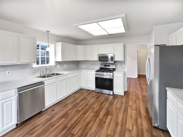 kitchen with sink, dark wood-type flooring, stainless steel appliances, white cabinets, and decorative light fixtures