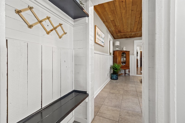 hallway featuring wood walls, light tile patterned floors, and wooden ceiling