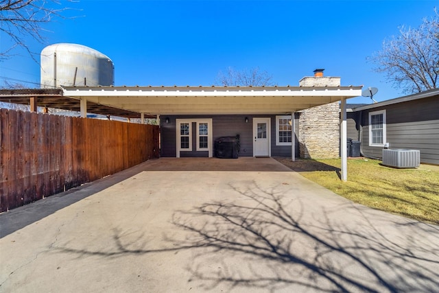 view of front of house with a front lawn, a carport, and central air condition unit