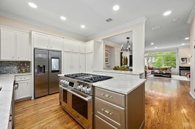 kitchen with white cabinetry, light stone countertops, ornamental molding, and stainless steel appliances