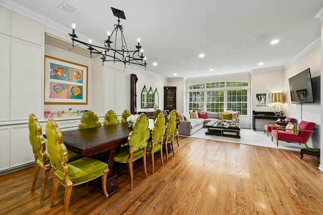 dining area with crown molding, a notable chandelier, and light wood-type flooring