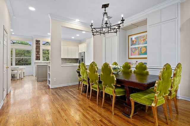 dining room with crown molding, a chandelier, and light hardwood / wood-style flooring