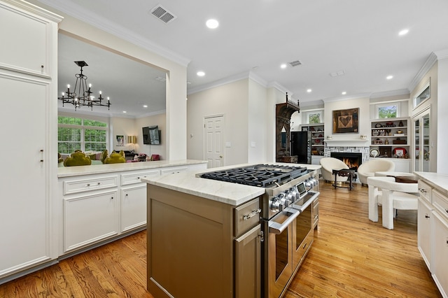 kitchen featuring a stone fireplace, crown molding, light wood-type flooring, double oven range, and white cabinets