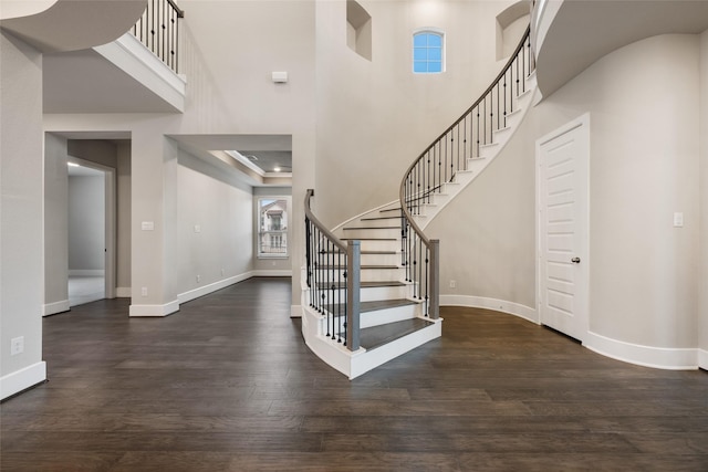 foyer with dark wood-type flooring and a towering ceiling