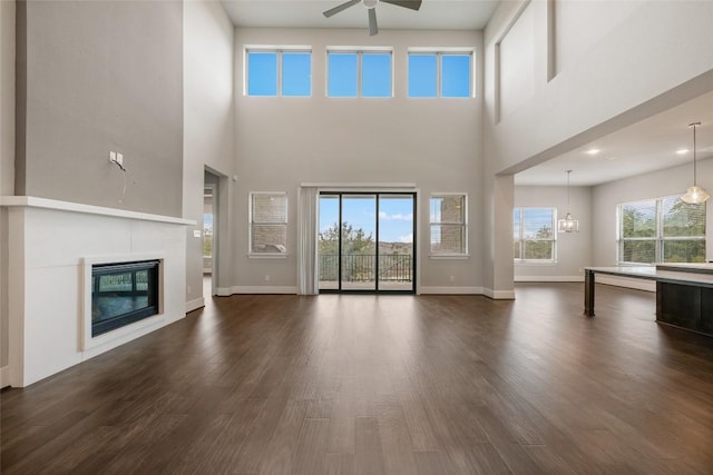 5801 Davenport Divide Rd, Austin, TX 78738 - unfurnished living room featuring a ceiling fan, dark wood-type flooring, a towering ceiling, and a fireplace