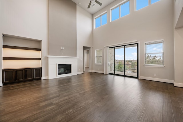 unfurnished living room featuring a towering ceiling and dark wood-type flooring