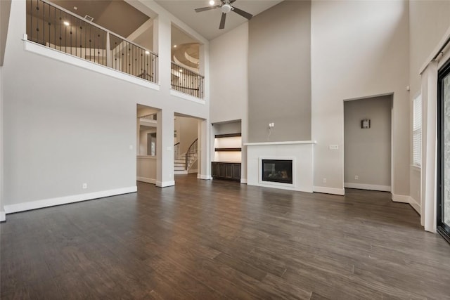 5801 Davenport Divide Rd, Austin, TX 78738 - unfurnished living room with a high ceiling, ceiling fan, baseboards, dark wood-style floors, and a glass covered fireplace