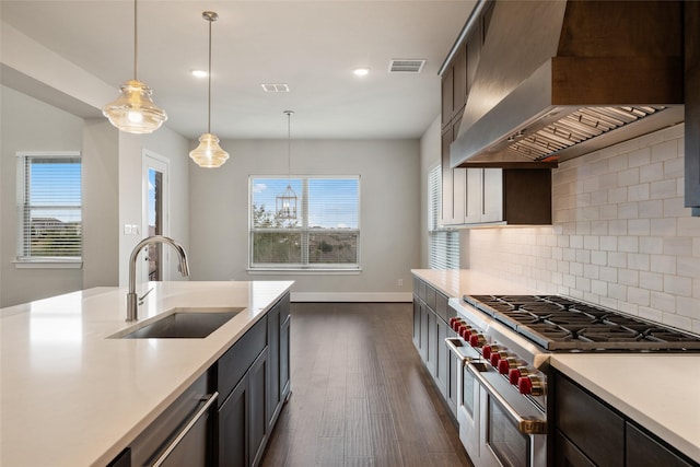 kitchen featuring pendant lighting, sink, appliances with stainless steel finishes, backsplash, and custom range hood