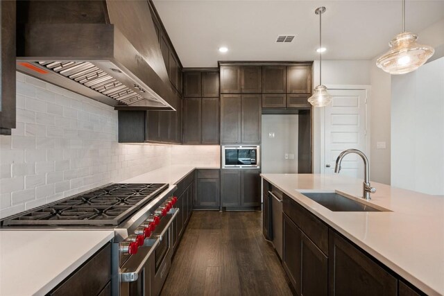 5801 Davenport Divide Rd, Austin, TX 78738 - kitchen with wall chimney range hood, a sink, stainless steel appliances, dark wood finished floors, and light countertops