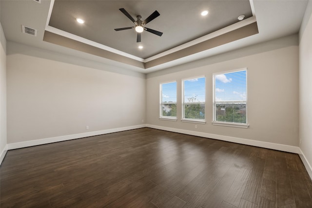 spare room with ceiling fan, dark hardwood / wood-style floors, and a raised ceiling