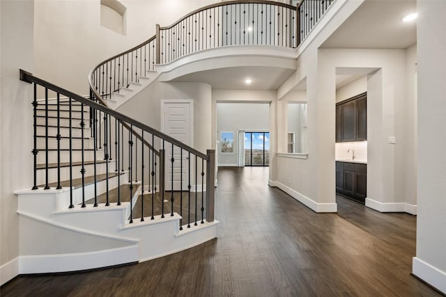 5801 Davenport Divide Rd, Austin, TX 78738 - foyer entrance featuring baseboards, dark wood-type flooring, a high ceiling, stairs, and arched walkways