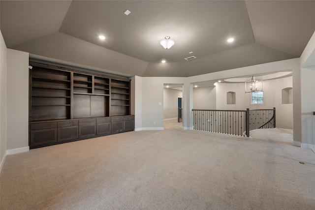 unfurnished living room featuring lofted ceiling, light colored carpet, and a raised ceiling