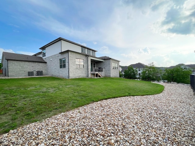 rear view of house featuring central AC and a lawn