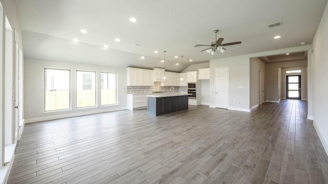 128 La Venta Loop, Liberty Hill, TX 78642 - unfurnished living room featuring vaulted ceiling, a ceiling fan, wood finished floors, and recessed lighting