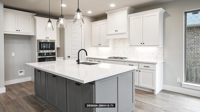 kitchen with appliances with stainless steel finishes, sink, a center island with sink, and white cabinets