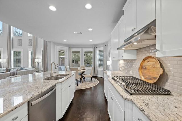 kitchen with sink, appliances with stainless steel finishes, white cabinetry, tasteful backsplash, and light stone counters