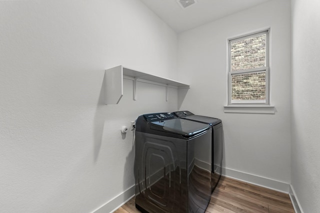 laundry area with hardwood / wood-style flooring and washing machine and dryer