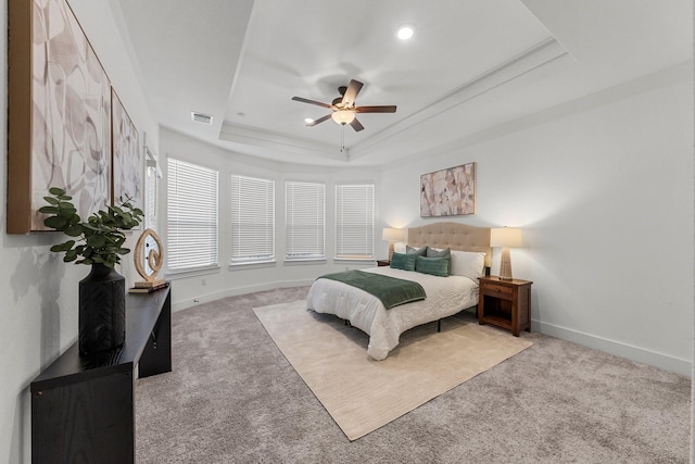 carpeted bedroom with ceiling fan and a tray ceiling