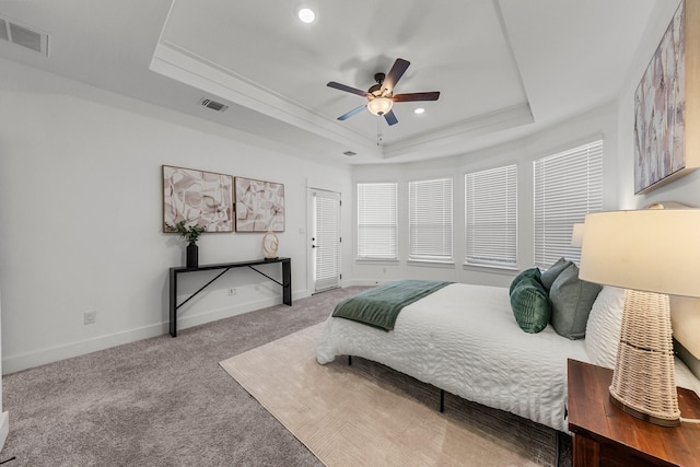 bedroom featuring light carpet, ceiling fan, and a tray ceiling