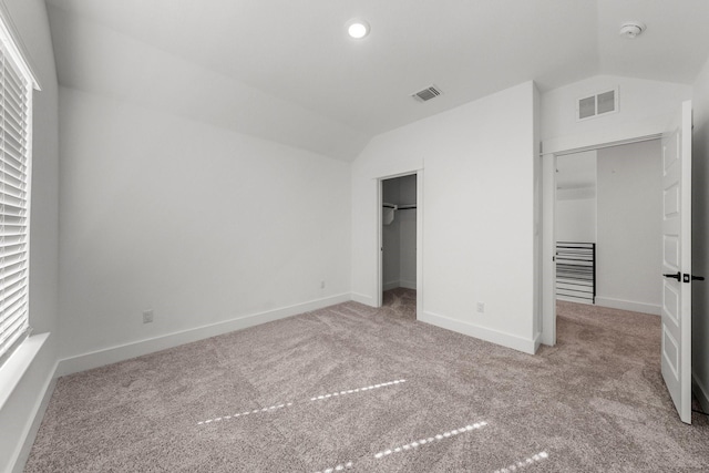 unfurnished bedroom featuring lofted ceiling, light colored carpet, and a closet