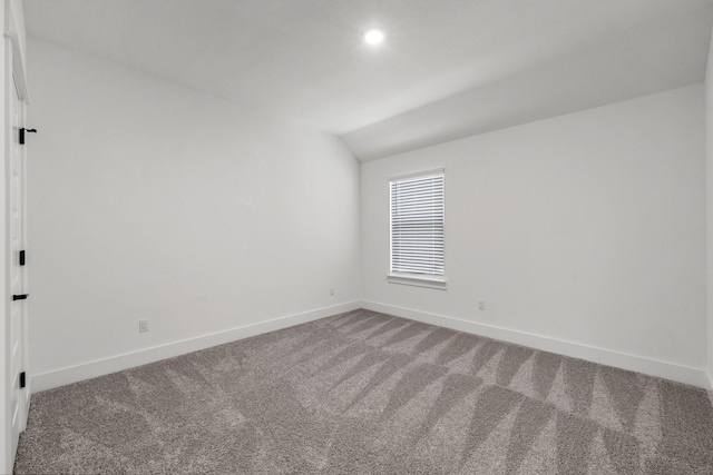 carpeted spare room featuring vaulted ceiling