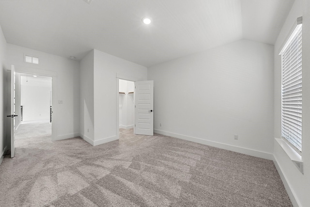 unfurnished bedroom with vaulted ceiling and light colored carpet