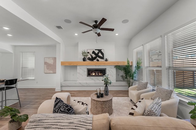 living room featuring hardwood / wood-style floors, built in shelves, a fireplace, and ceiling fan