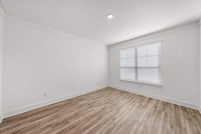 empty room with crown molding and light wood-type flooring