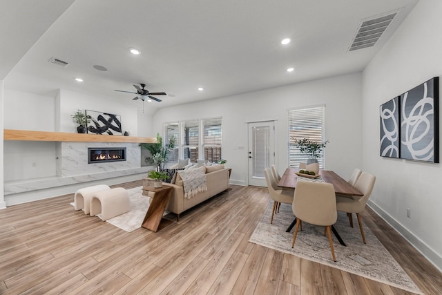 interior space featuring ceiling fan, plenty of natural light, a high end fireplace, and light hardwood / wood-style floors