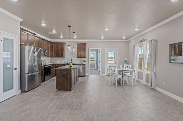 kitchen featuring tasteful backsplash, a textured ceiling, a kitchen island, pendant lighting, and stainless steel appliances